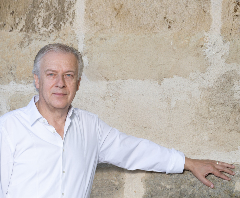 Hannes Rathammer in weißem Hemd vor einer Steinmauer